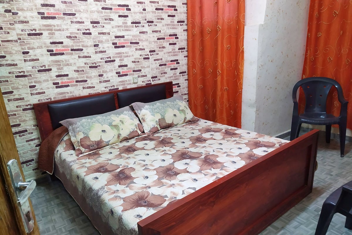 A room with a bed, a chair, and a patterned wall.
