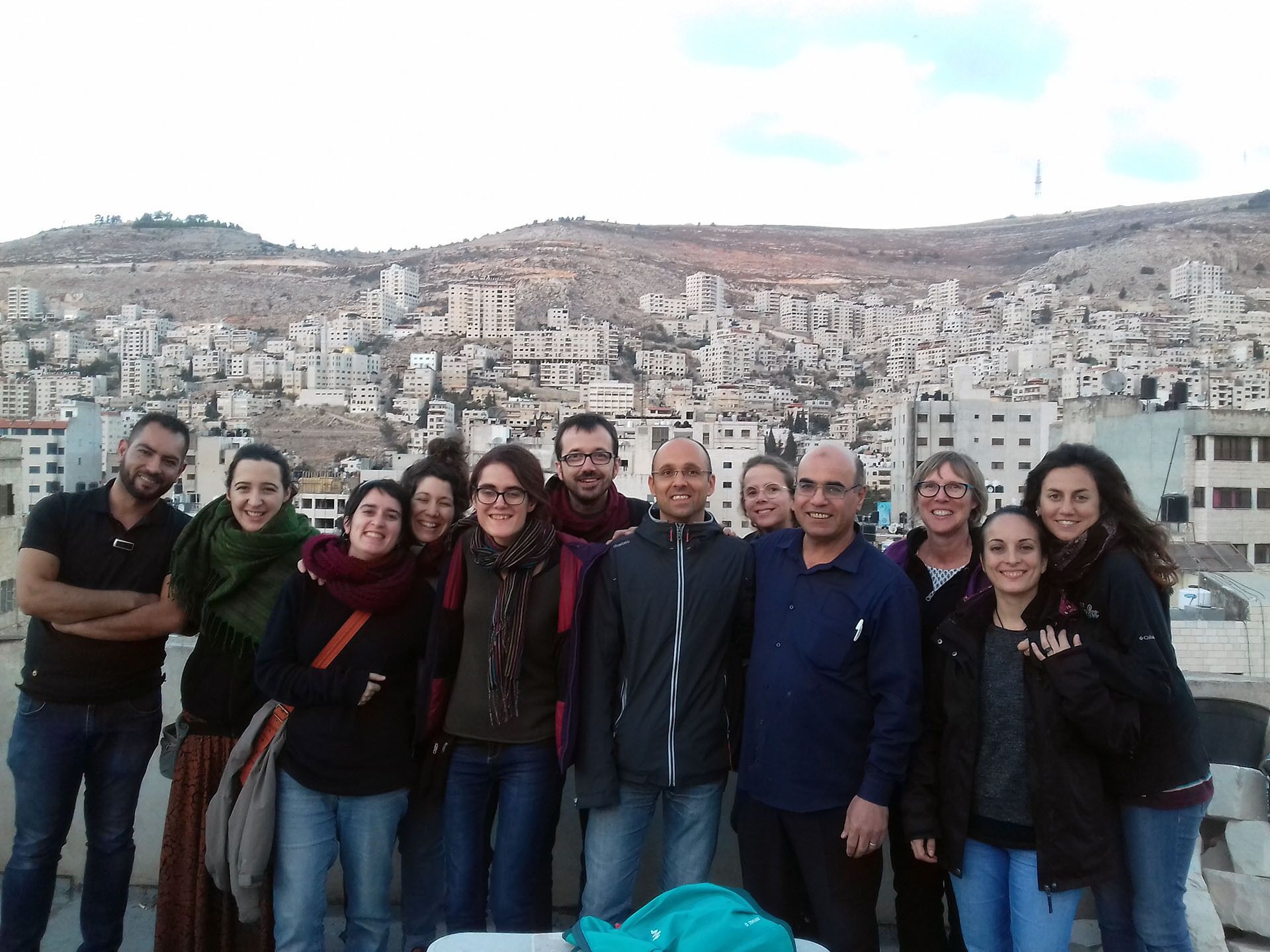 A group of people posing on a rooftop with a cityscape in the background.