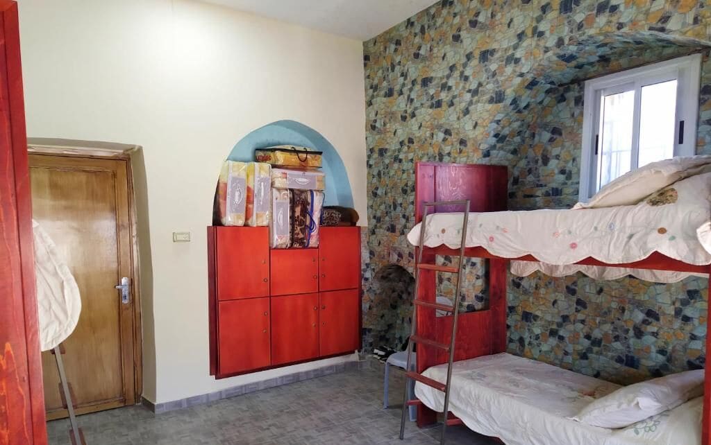 Ein Zimmer mit Etagenbetten, einem Kleiderschrank und einem Fenster.