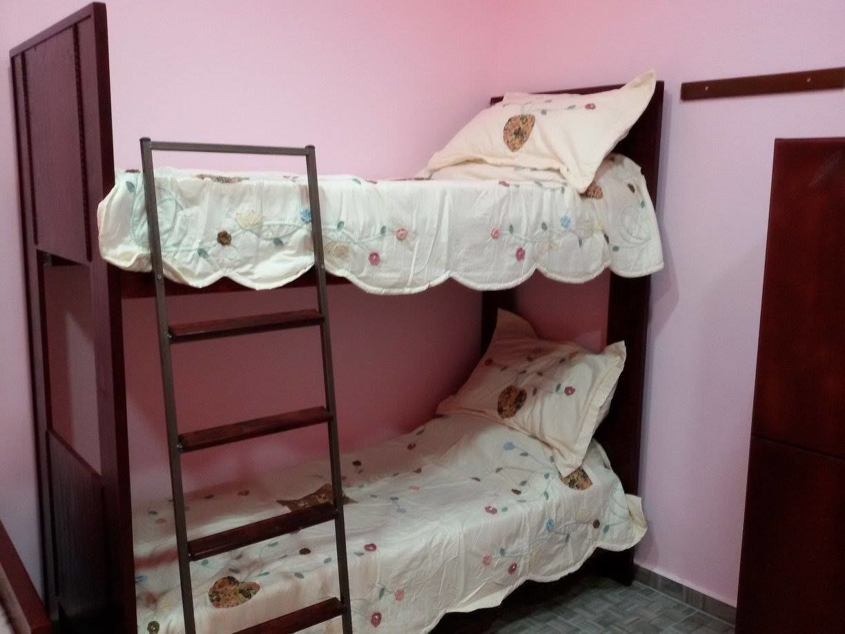 A bunk bed with a ladder, floral bedding, and a pink wall.