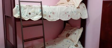 A bunk bed with a ladder, floral bedding, and a pink wall.