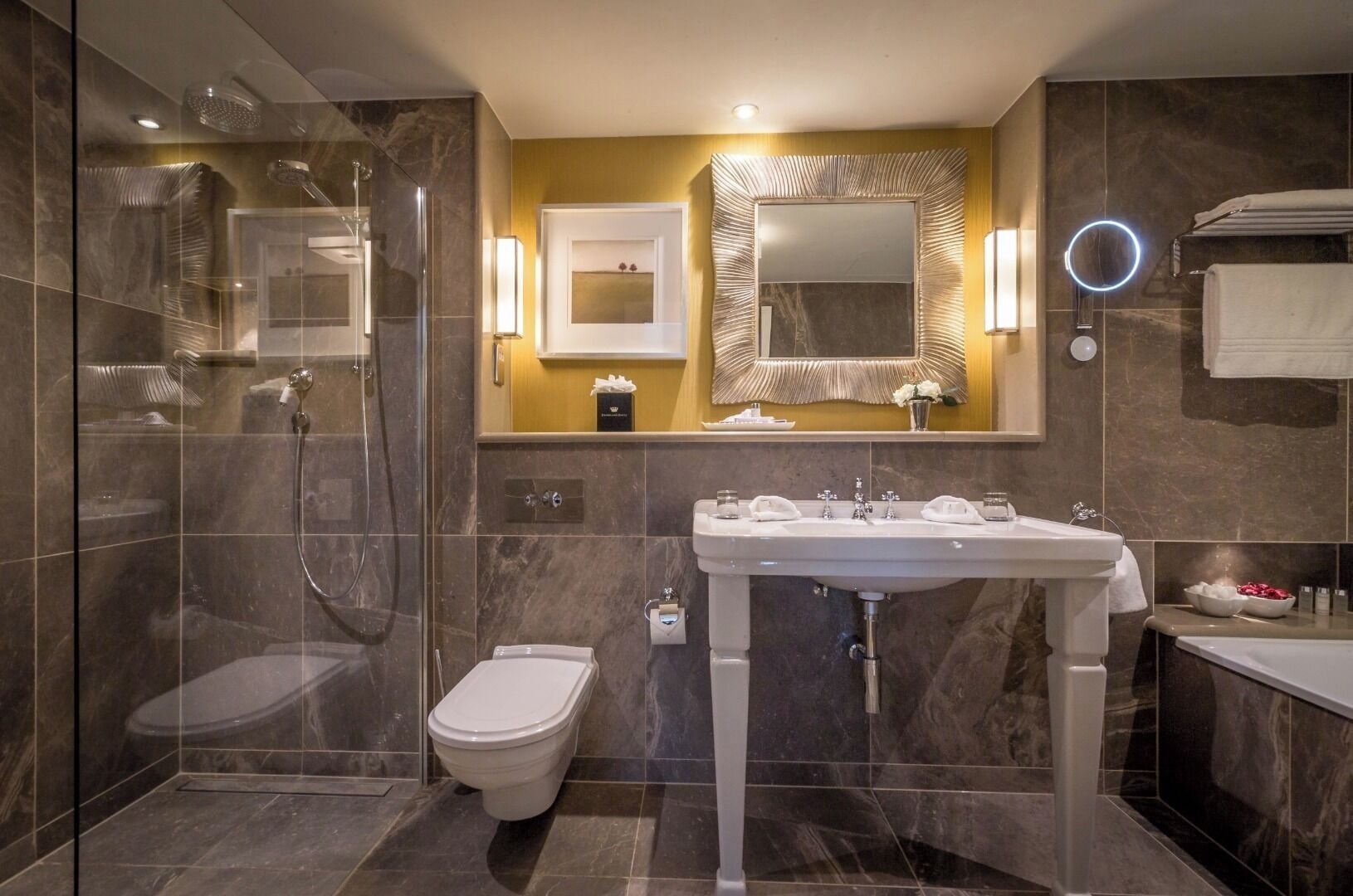 A modern bathroom with a glass-enclosed shower, a toilet, a sink with a vanity, and a large mirror.