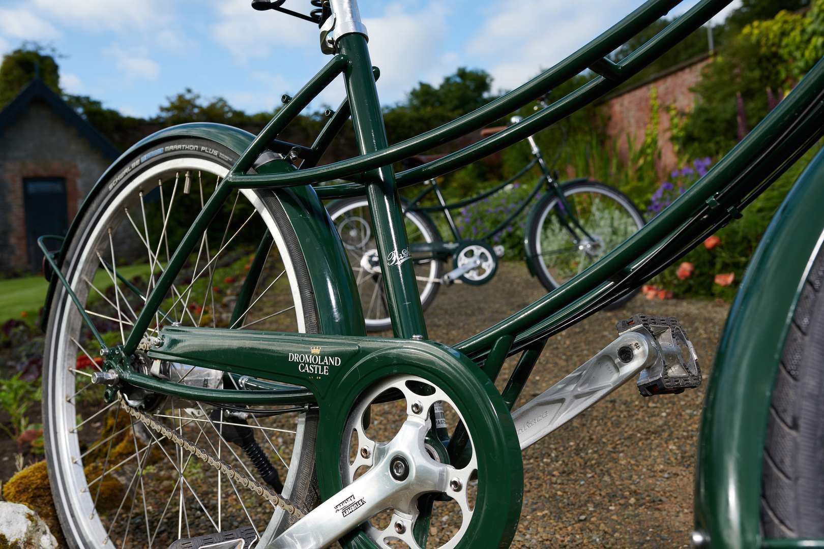 A green bicycle with a Dromoland Castle label, a chain, and a rear wheel.