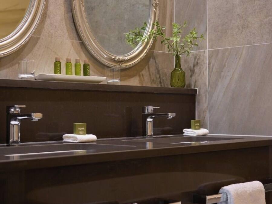 A bathroom with two mirrors, a sink, and a towel rack.