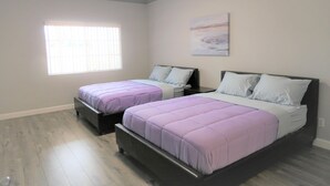 Een slaapkamer met twee bedden, een raam en een schilderij aan de muur.