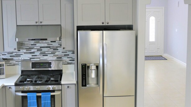 Een moderne keuken met roestvrijstalen apparatuur, waaronder een fornuis, oven en koelkast.