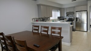 Een moderne keuken met grijze kastjes, een centraal eiland en roestvrijstalen apparatuur.