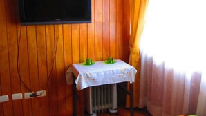 A room with a television mounted on a wooden wall, a radiator, and a table with a tablecloth. - Ventanas del Lago (Puerto Varas)
