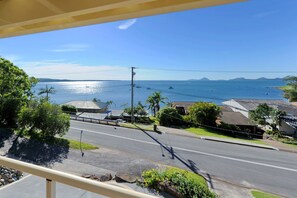 A coastal road with houses and a clear view of the ocean and distant mountains. - Seaside Serenity Soldiers Point (Soldiers Point)