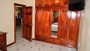 A room with a wooden wardrobe, a television mounted on the wall, and a tiled floor. - Book now and u can save 20%OFF JUNE JULY 
FOR EARLY BIRD SALE IN SUMMER BOOKING  (Ochio Rios)