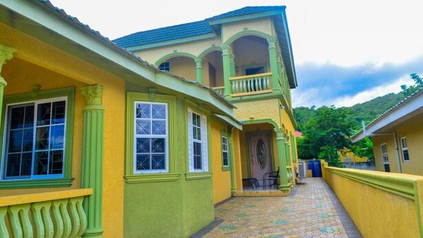 A yellow building with a balcony and multiple windows. - Book now and u can save 20%OFF JUNE JULY 
FOR EARLY BIRD SALE IN SUMMER BOOKING  (Ochio Rios)