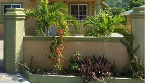 A two-story house with a tiled roof, a balcony, and a garden with various plants. - Book now and u can save 20%OFF JUNE JULY 
FOR EARLY BIRD SALE IN SUMMER BOOKING  (Ochio Rios)
