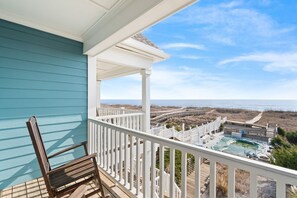A balcony with a view of the beach and a pool area. - Majak Moments: Exceptionally spacious oceanfront 7BR home in Holden Beach. (Holden Beach)