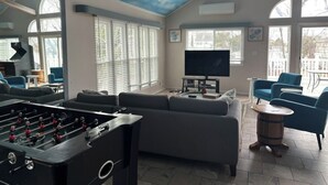 A spacious living room with a foosball table, a large flat-screen TV, and comfortable seating.
