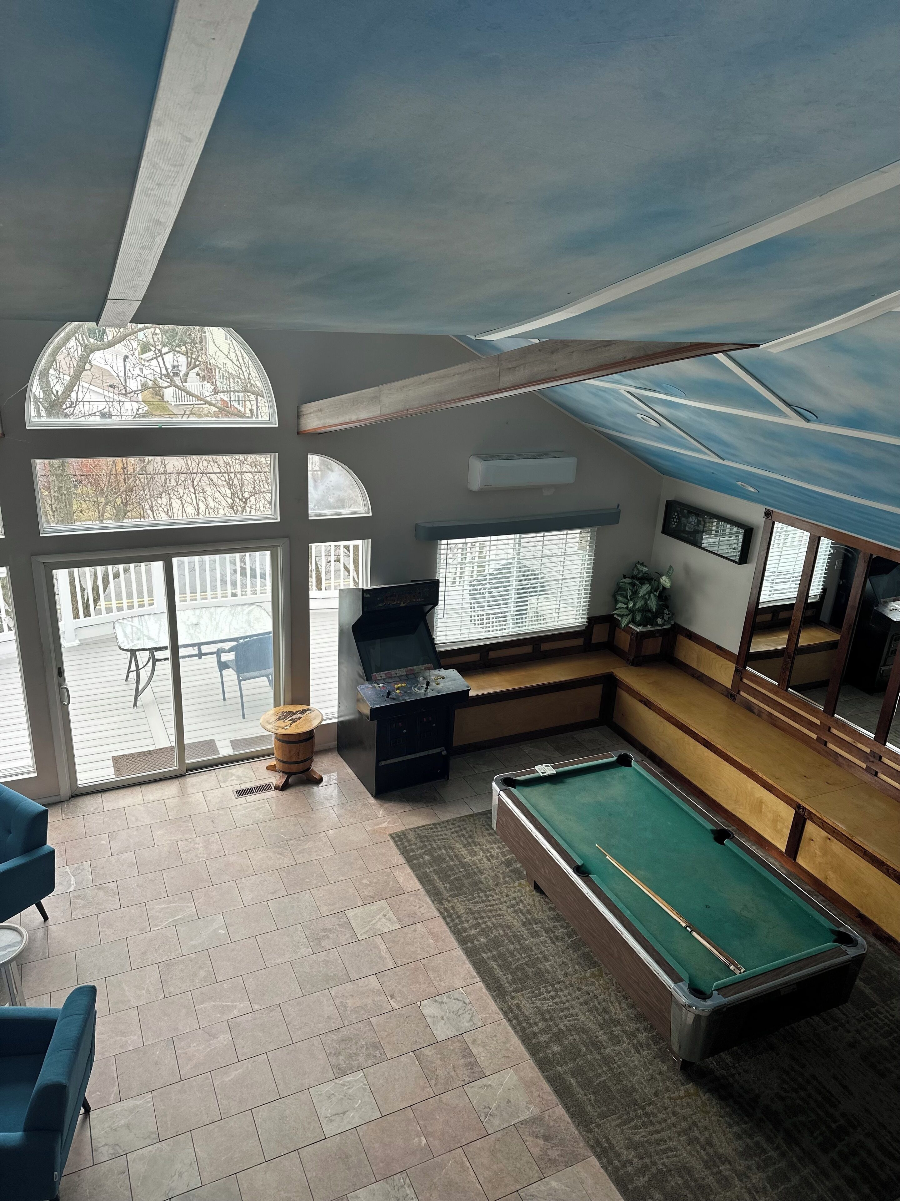 Ein Billardtisch in einem Raum mit Blick auf eine Terrasse, ein Kicker und eine Sitzecke mit einer Bank.