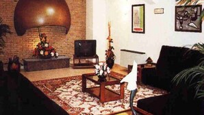 A living room with a brick wall, a large ceiling light, a television, and a sofa. - Hotel La Seu (La Seu d'Urgell)
