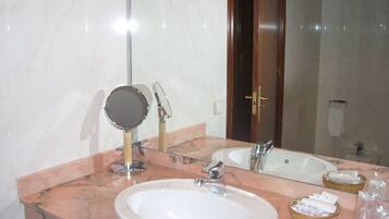 Un baño con lavamanos de mármol, un espejo, toallero y zona de ducha.