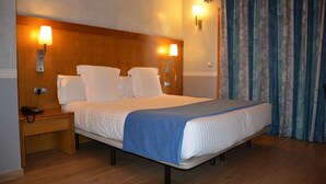 Une chambre d’hôtel avec un grand lit, des lampes de chevet, une table de chevet en bois et un téléphone.