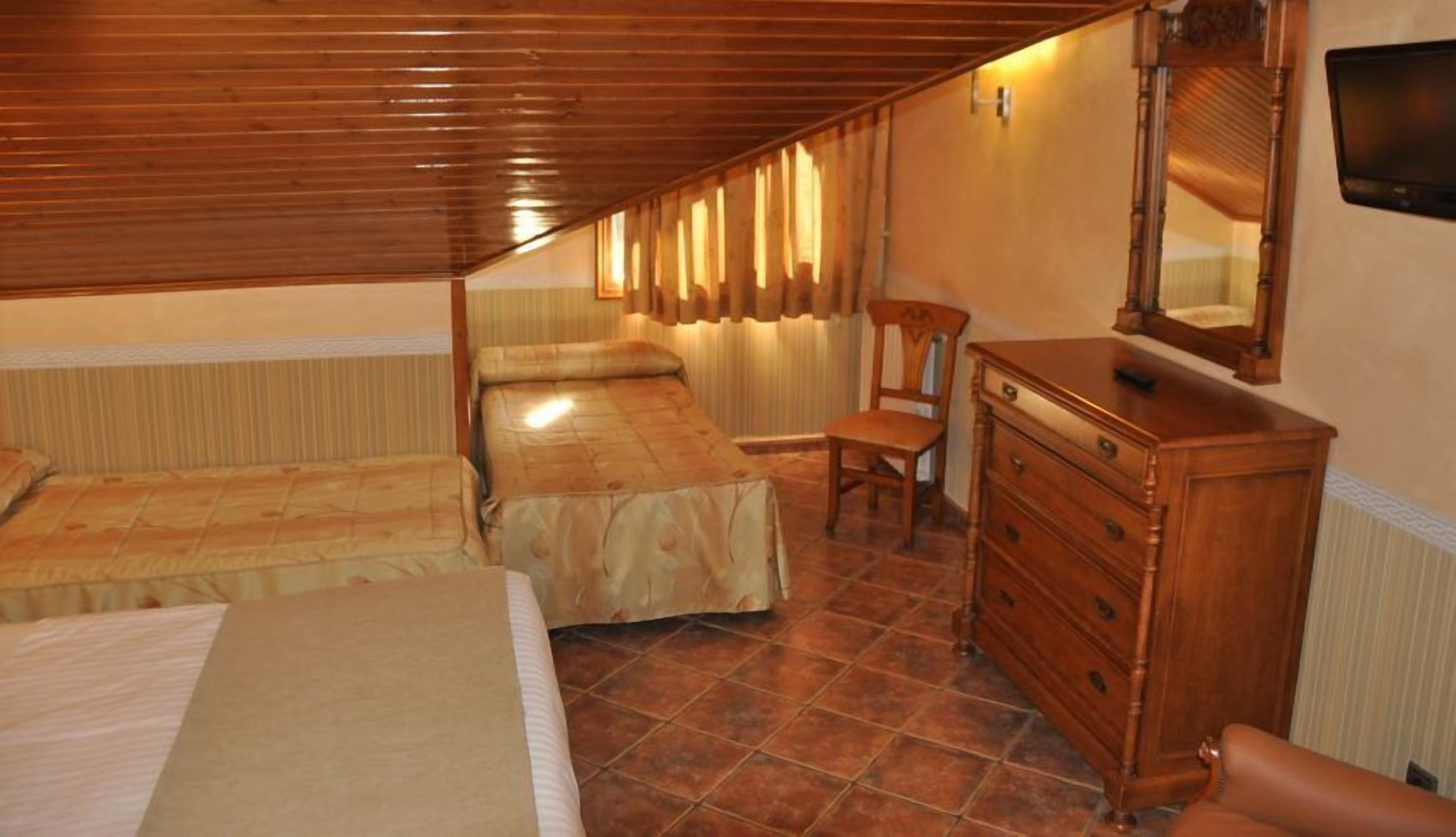 A bedroom with two beds, a wooden dresser, a chair, and a television.
