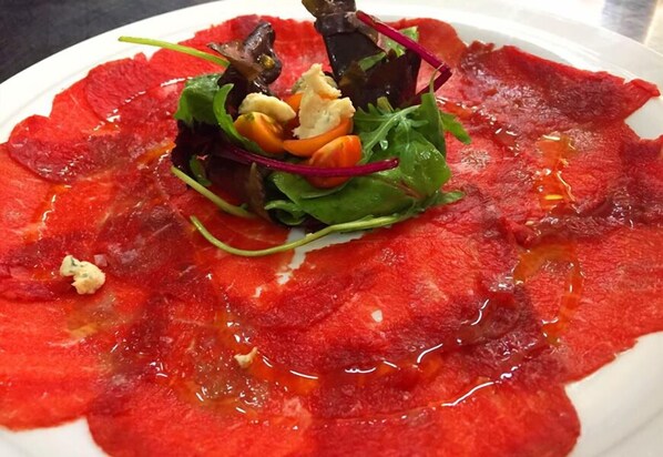 Un plato de pescado crudo con guarnición de hojas verdes y vegetales.