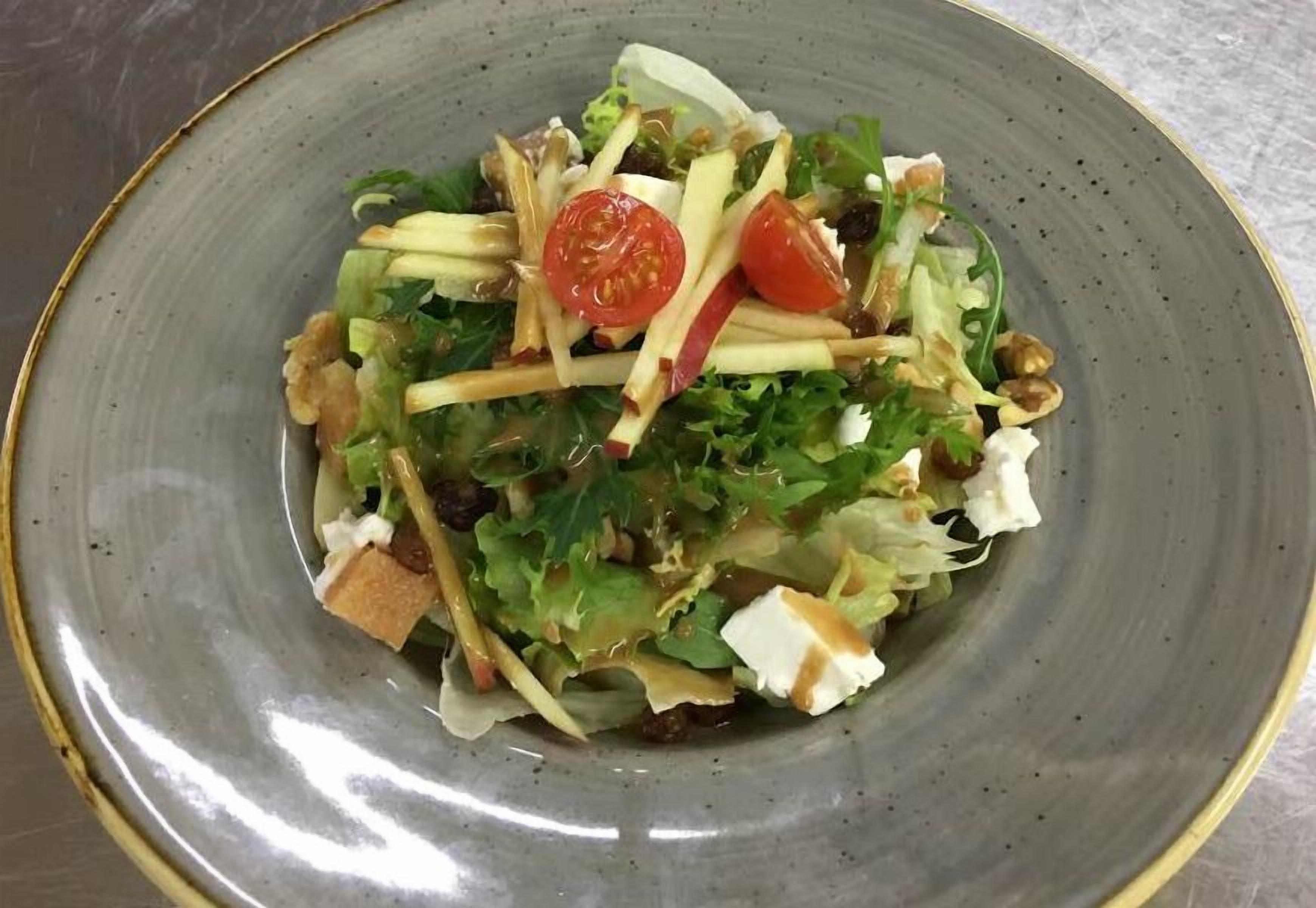 Uma salada com diversos vegetais e frutos secos.