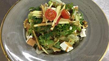 Uma salada com diversos vegetais e frutos secos.