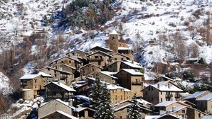 Un ensemble de bâtiments en pierre aux toits enneigés, se dressant sur un coteau également recouvert de neige.