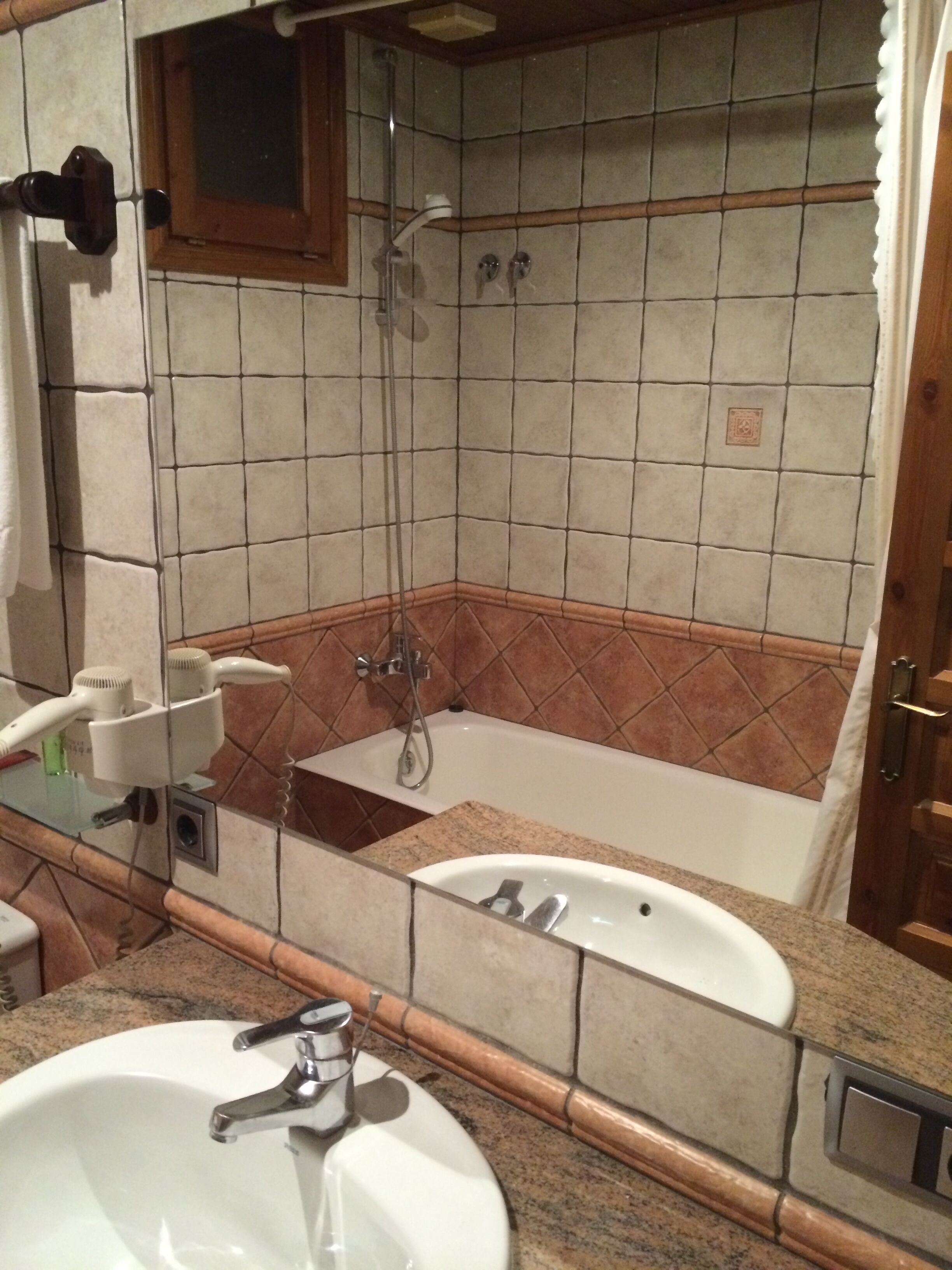 Un baño con lavamanos, espejo y ducha.