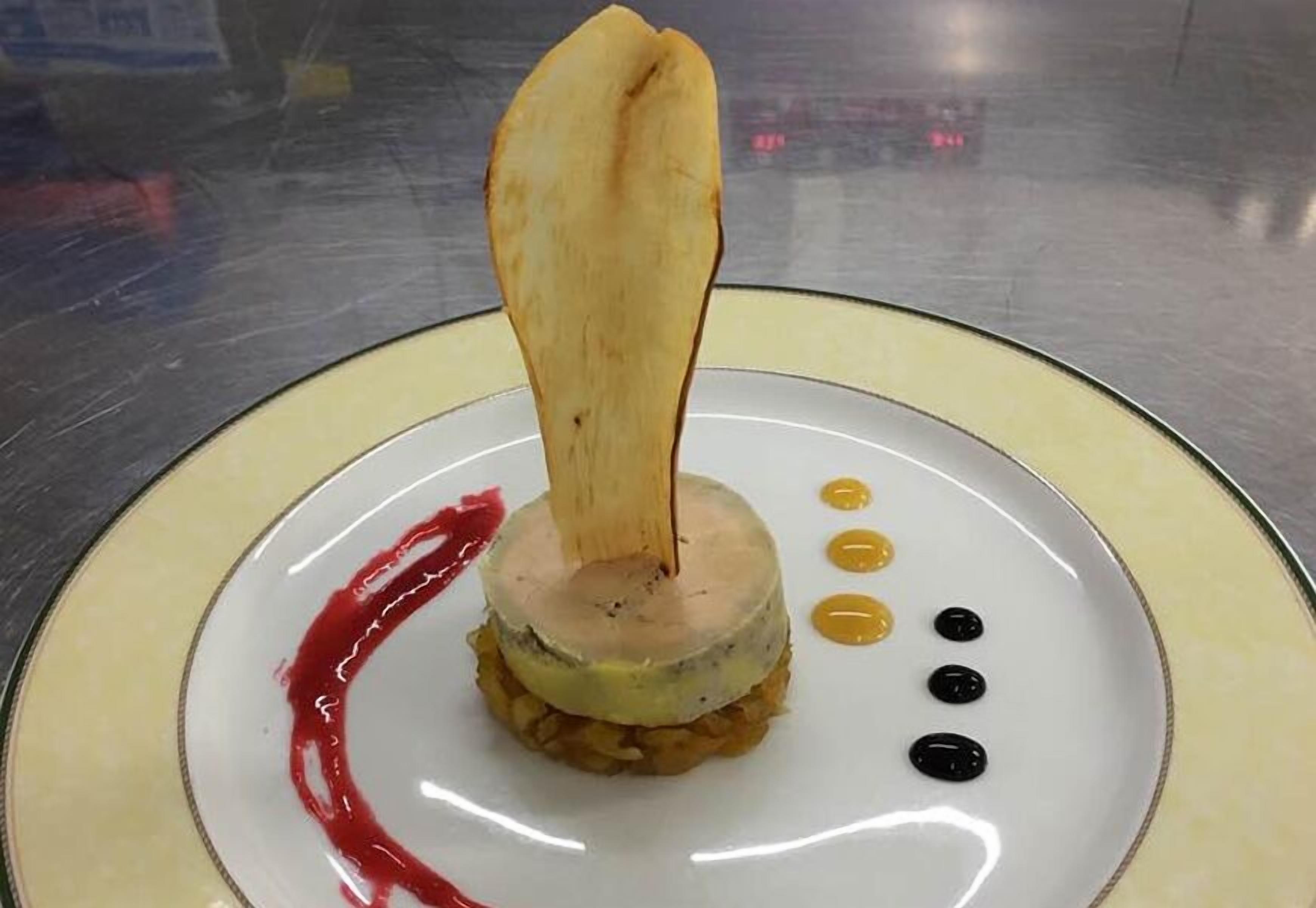 Een bord met een gelaagde maaltijd, saus en enkele zwarte stipjes.