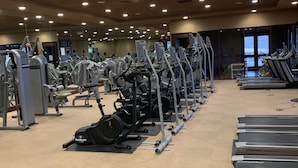 Ein Fitnessstudio mit verschiedenen Trainingsgeräten, Laufbändern und einem Teppichboden.