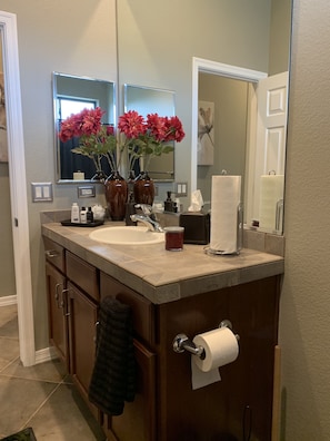 A bathroom with a sink, mirror, and two vases with flowers.