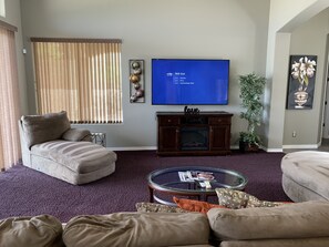 A living room with a large flat-screen TV, a fireplace, and a comfortable seating area.