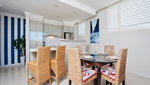 A modern kitchen with white cabinets, a built-in oven, and a stainless steel refrigerator.