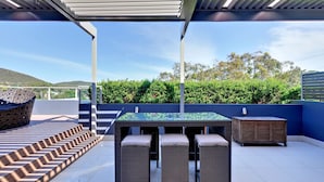 An outdoor patio with a table and chairs, a covered seating area, and a view of the landscape. - Aura Apartments U12 Shoal Bay Beach Views (Shoal Bay)