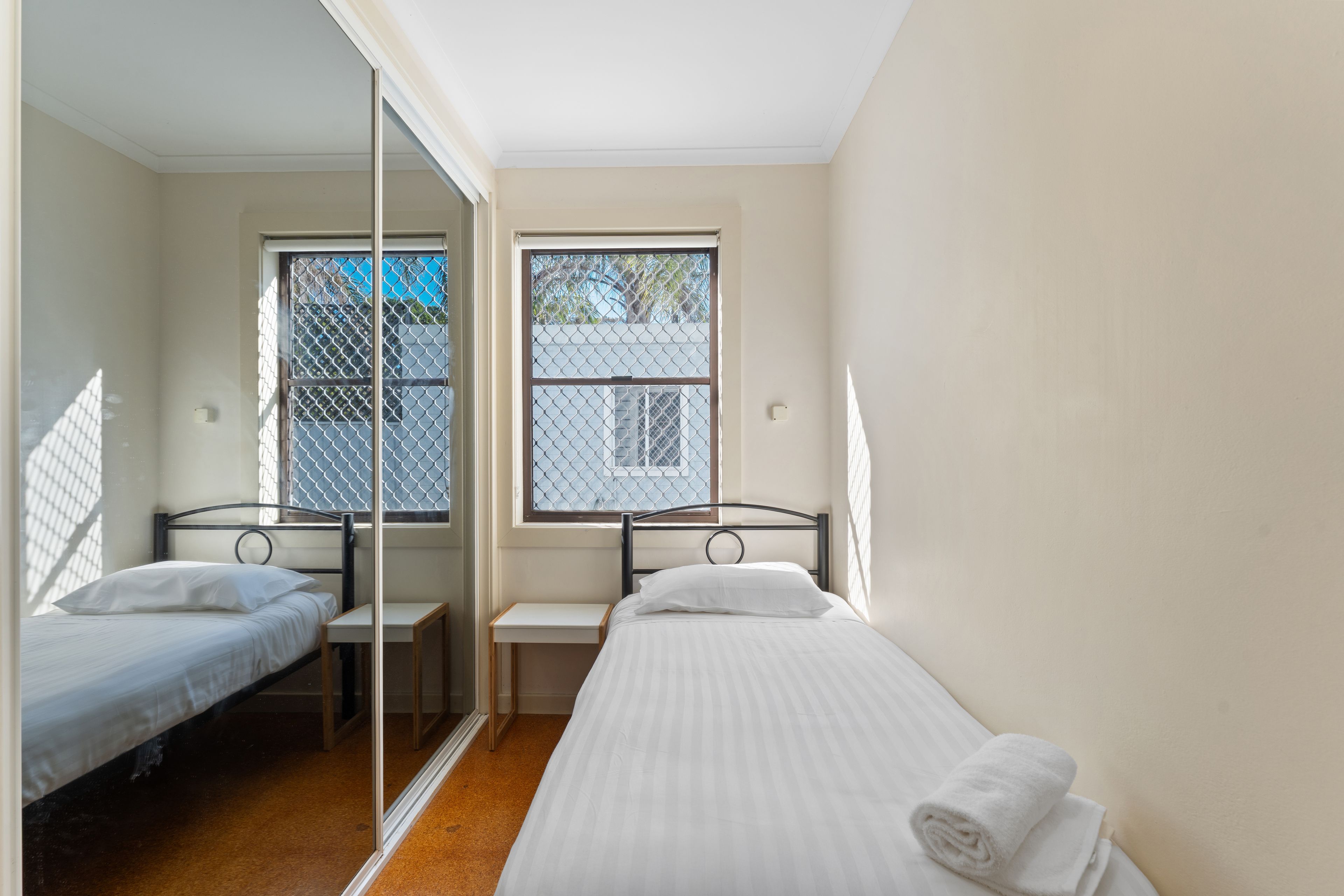 Un dormitorio con dos camas individuales, una mesita y un espejo.