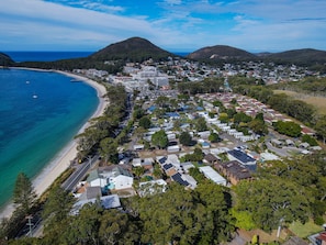 A coastal town with a beach, residential buildings, and hills in the background. - Shoal Bay Av 1 Ground floor (Shoal Bay)