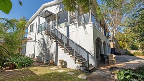 A two-story house with a staircase, outdoor seating, and a garden. - Beach break garden unit! (Shoal Bay)