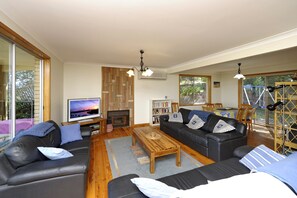 Ein Wohnzimmer mit einer Couch, einem Couchtisch, einem Kamin, einem Fernseher und einem Bücherregal.