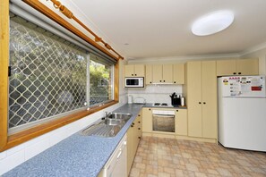 A kitchen with a window, sink, microwave, stove, and refrigerator.