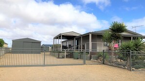 A property with a fenced driveway, a covered outdoor area, and a building with a sign indicating a sale. - Livin' The Dream ~ Spacious  ~  Off Peak Special! WIFI Available (Point Turton)