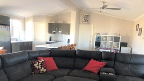 A modern living room with a sectional sofa, a kitchen in the background, and a dining area. - Livin' The Dream ~ Spacious  ~  Off Peak Special! WIFI Available (Point Turton)
