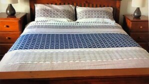 A bed with a wooden headboard, two bedside tables with lamps, and a patterned bedspread. - Livin' The Dream ~ Spacious  ~  Off Peak Special! WIFI Available (Point Turton)