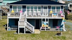 A two-story building with a balcony, a staircase, and a small porch area. - Experience beachfront living at Sandy Bottoms in Holden Beach, NC—perfect for families! (Holden Beach)