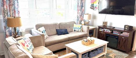 A living room with a sofa, coffee table, TV, and a bookshelf.