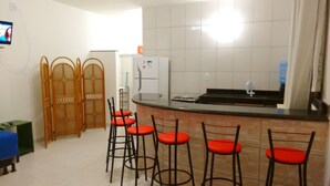 Una cocina con refrigerador, estufa y taburetes de bar.