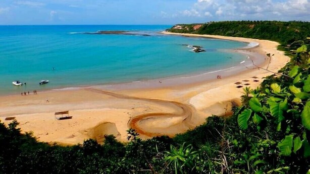 Una playa con aguas turquesas cristalinas, una orilla arenosa y algunos barcos.