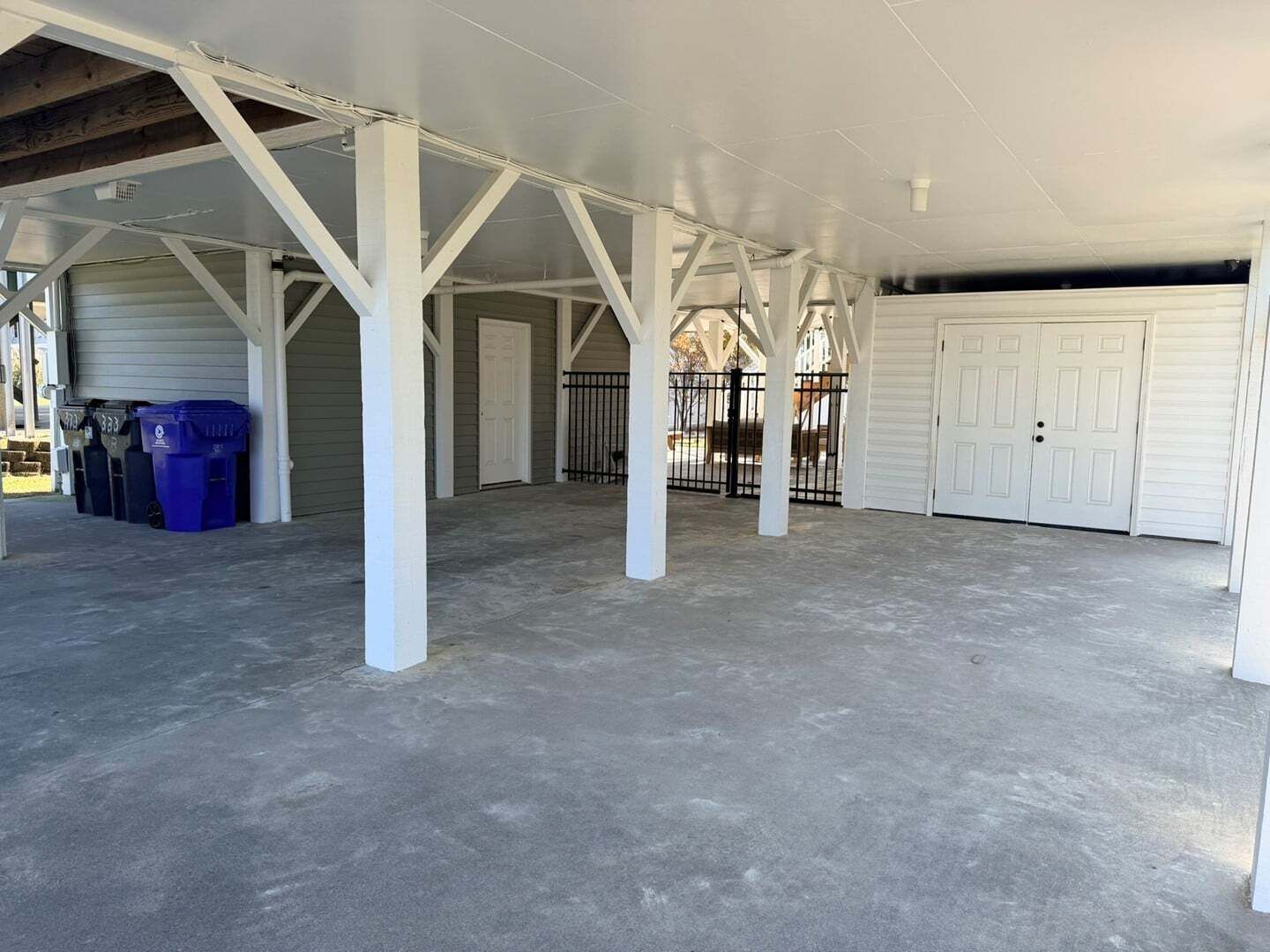 A spacious covered garage with white pillars, concrete floor, and two garage doors.