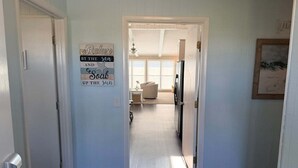 A hallway leading to a living area with a refrigerator, a sofa, and a window. - Enjoy oceanfront views at How Sweet The Sound in Holden Beach, NC; perfect for families. (Holden Beach)
