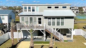 A two-story house with a balcony, a staircase, and a small deck area. - Enjoy oceanfront views at How Sweet The Sound in Holden Beach, NC; perfect for families. (Holden Beach)