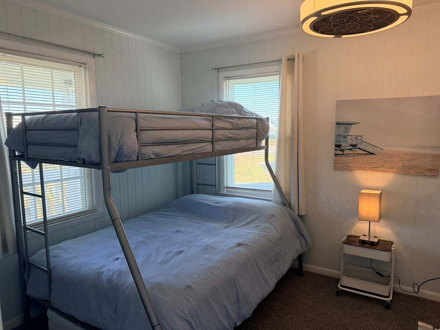 Une chambre avec un lit superposé, une petite table et une lampe.